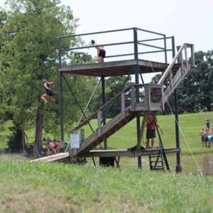 Treehouse vilalge kids having fun in the summer jumping into the pond at summer camp, Shepherd's Fold Ranch.