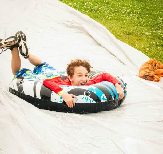 Child sliding down a slip and slide on inflatable tube.