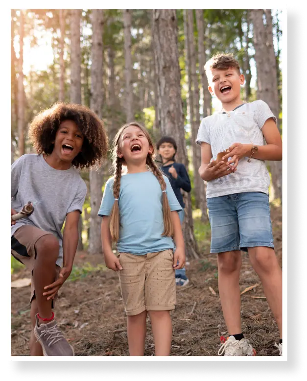 Children laughing together in a forest background.