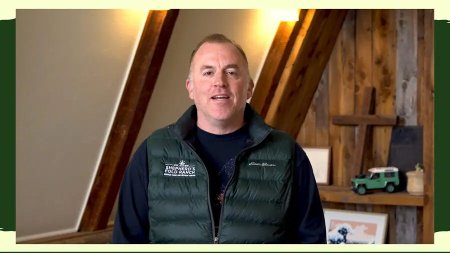 Man in vest speaks indoors at Shepherd's Fold Ranch.