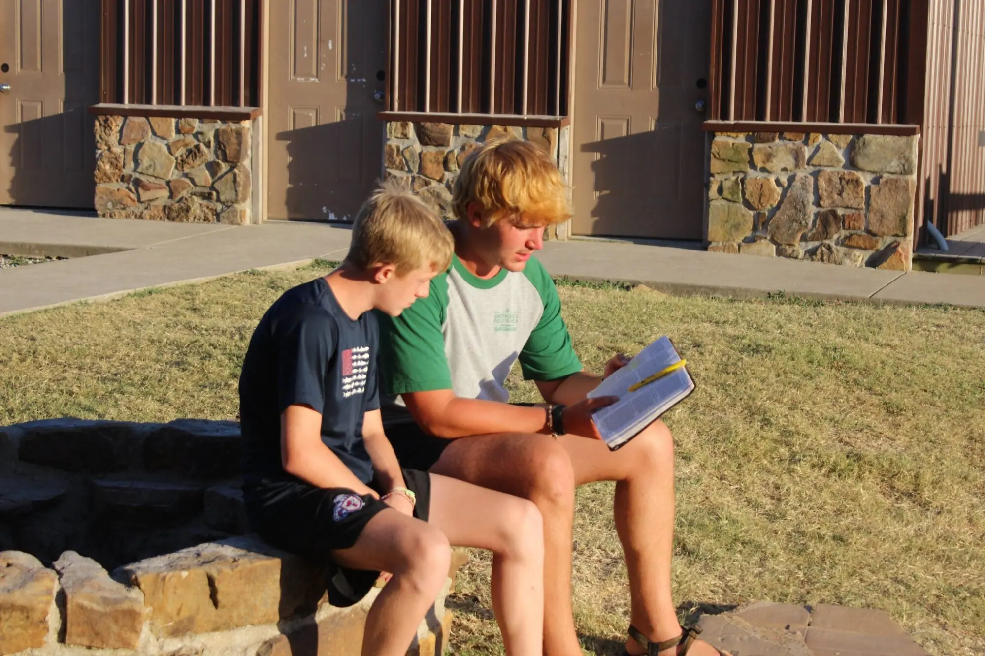 Two people reading the Bible outdoors on sunny day.