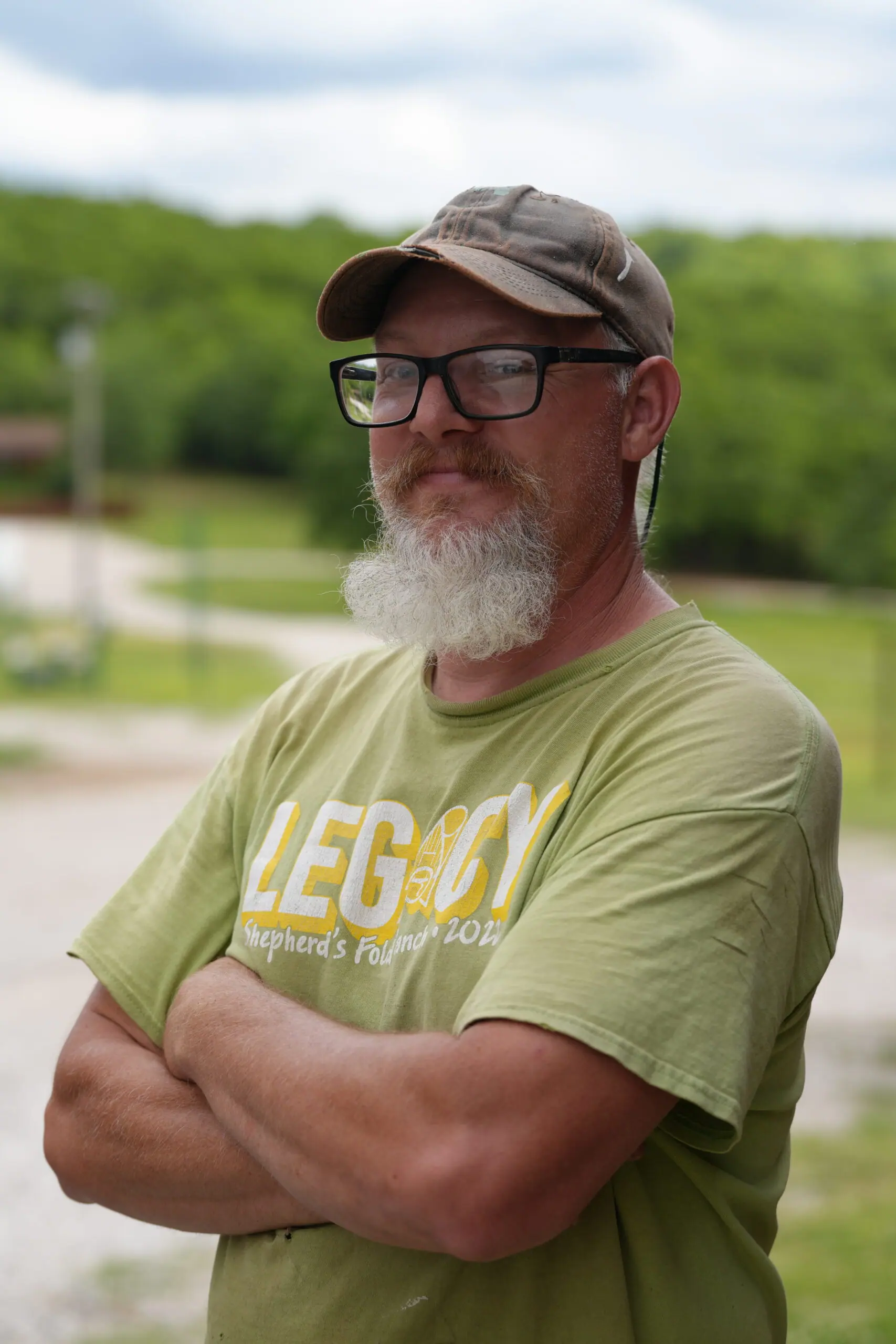 Person outdoors wearing a green shirt and cap.