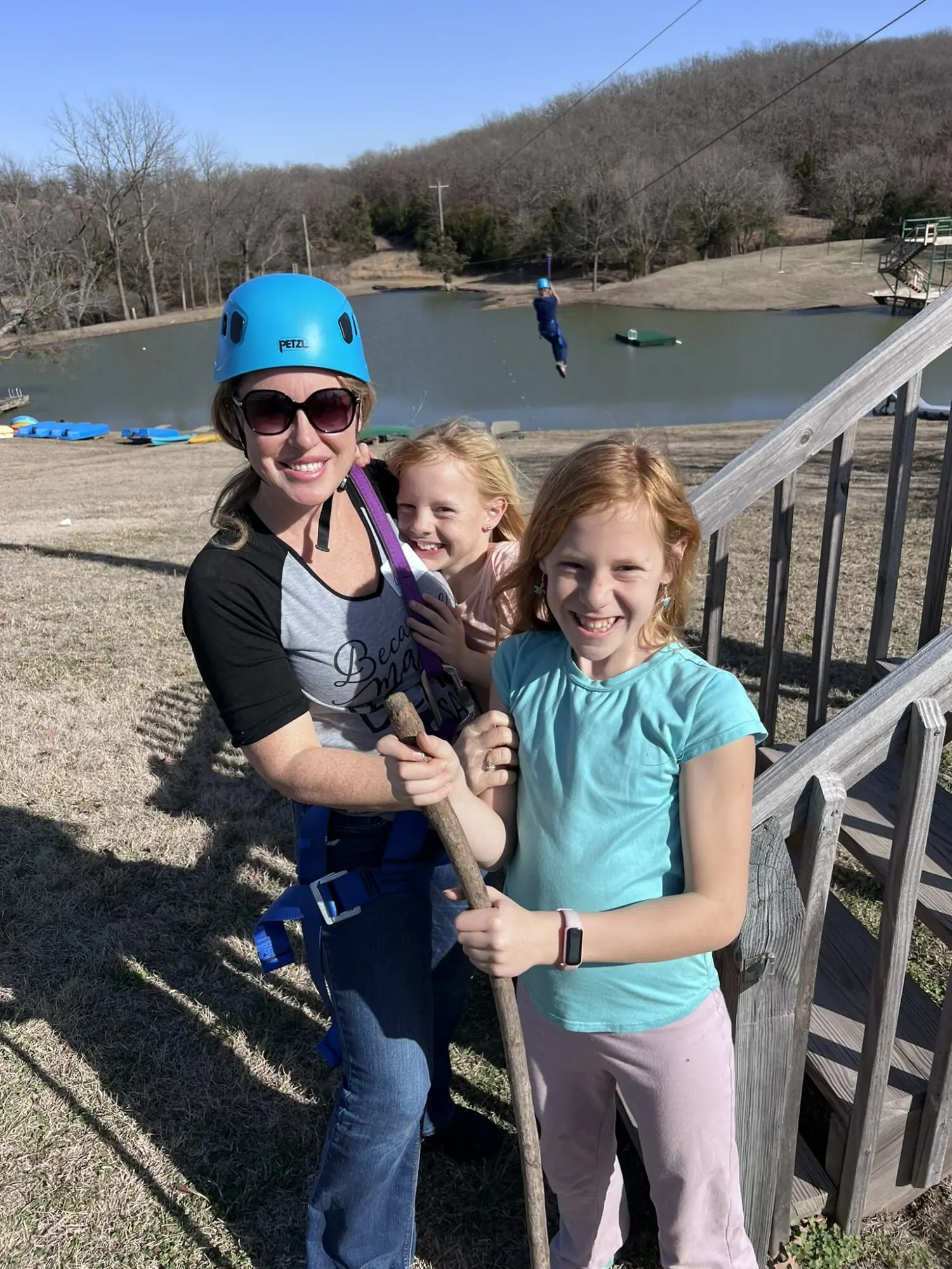 Family enjoying ziplining adventure near pond.