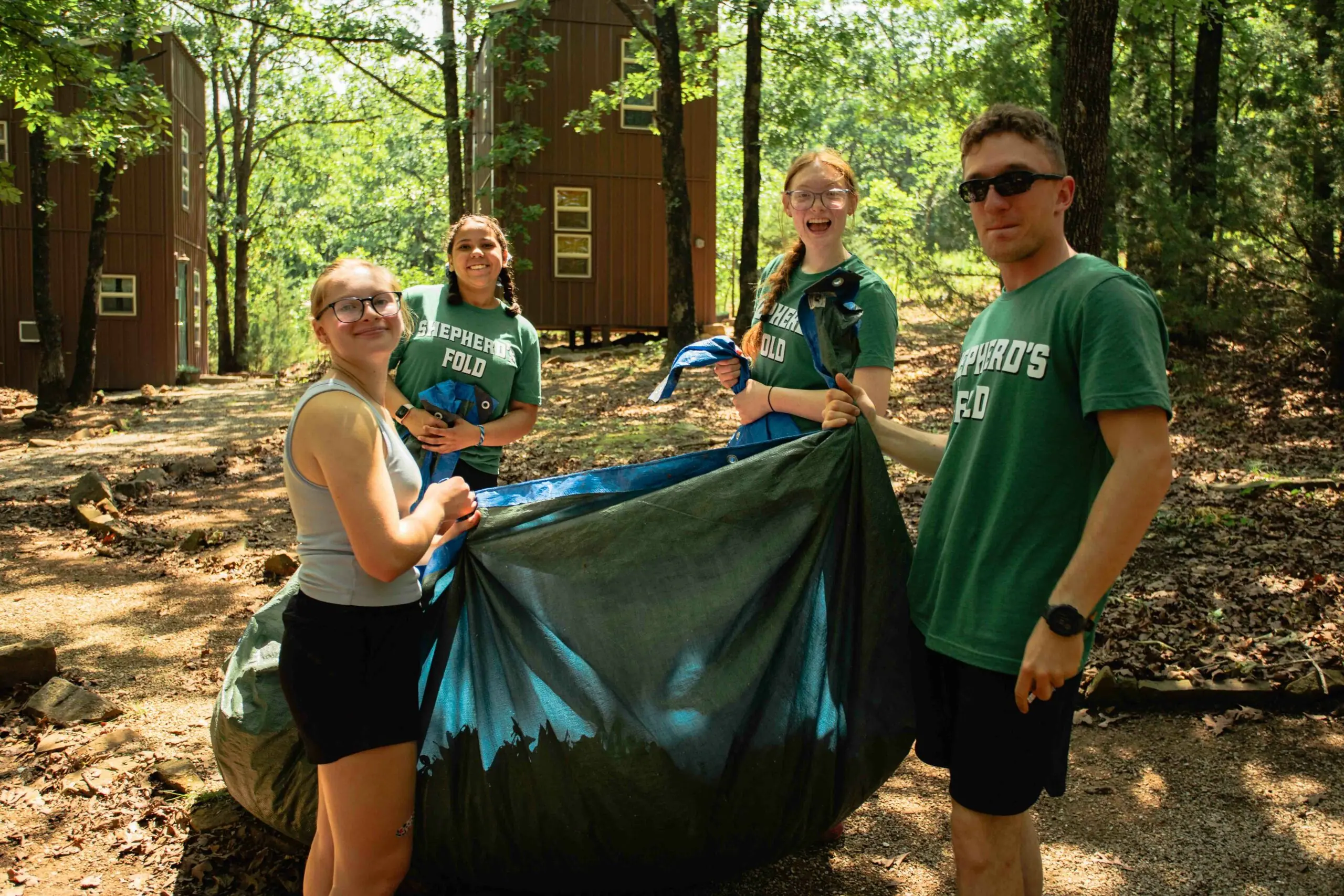 Four people standing in the woods at Shepherd's Fold Ranch during camp beautification day