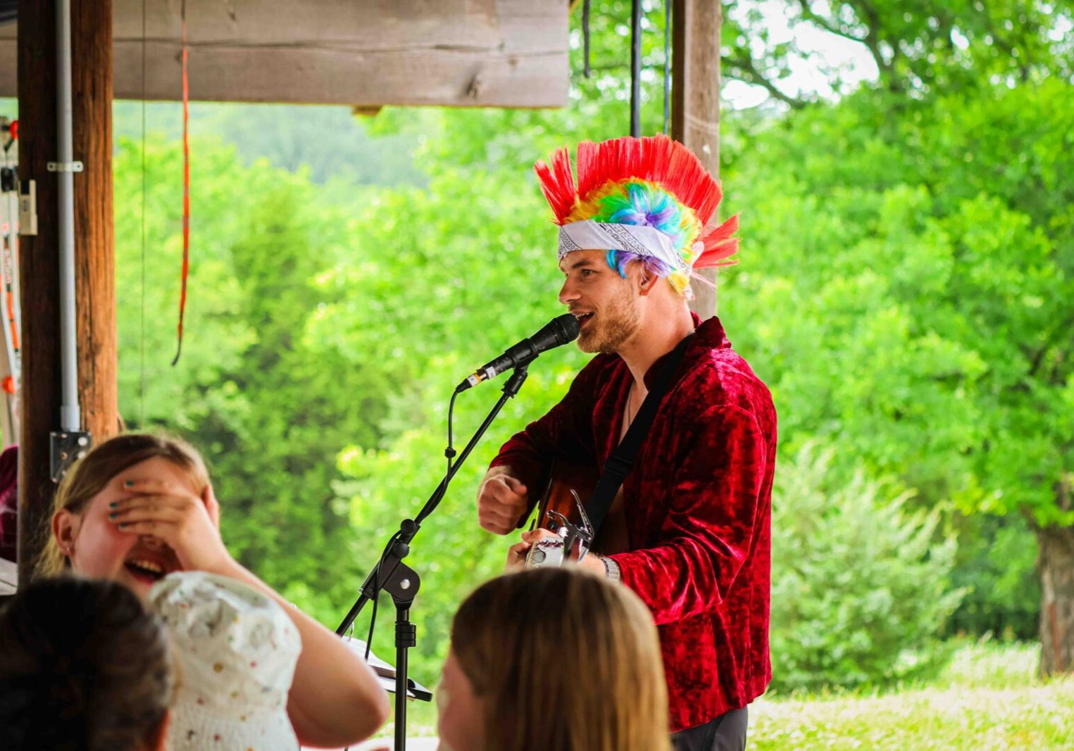 Man in colorful wig sings outdoors.